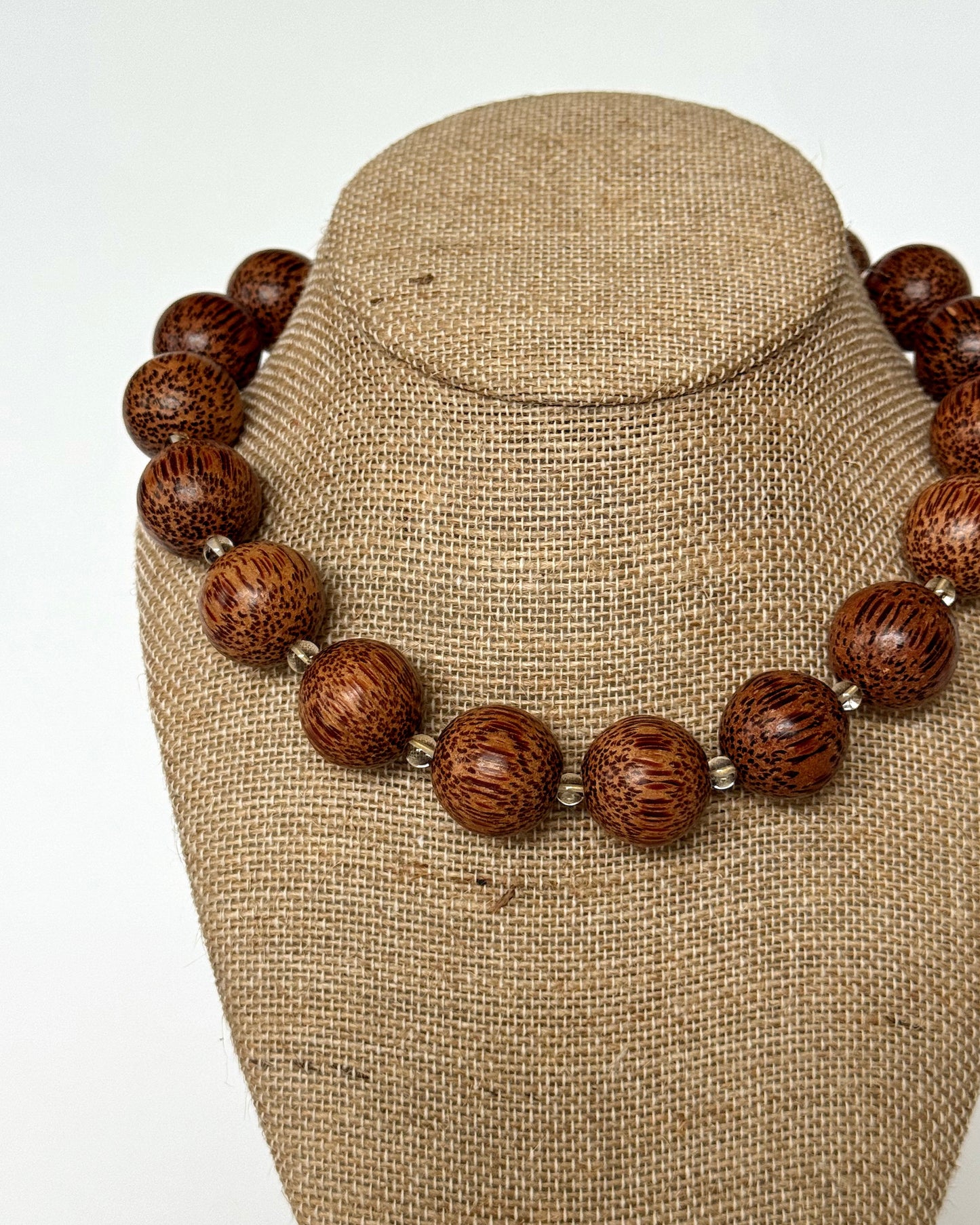 Necklace with brown wooden beads on a beige bust